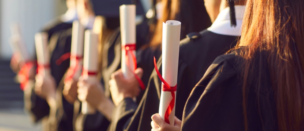 Students holding degree scrolls at graduation